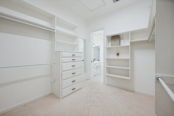 Primary bedroom spacious walk-in closet features ample storage, organized shelving, and convenient access to an adjoining bathroom.