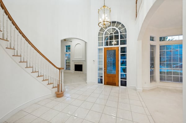 Bright entrance hall featuring a grand staircase, large windows, and modern tile flooring for a welcoming atmosphere.