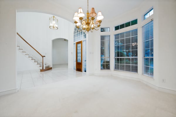 Bright and inviting living space featuring large windows, high ceilings, and an open staircase layout.