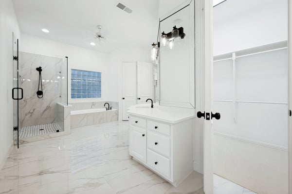 Spacious primary bathroom featuring modern fixtures, a luxurious tub, and ample storage in a sleek design.