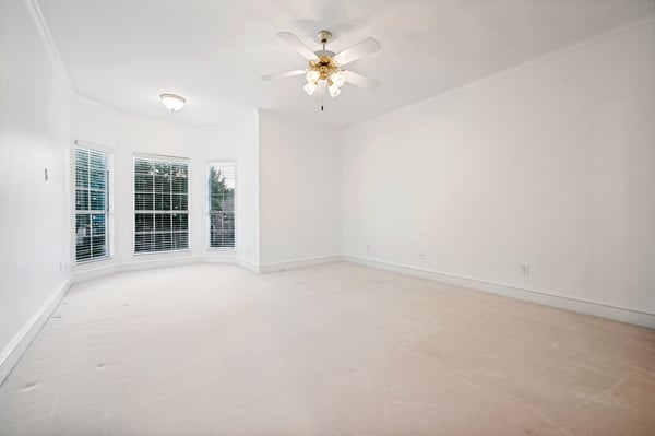 Bright, spacious room with large windows and a ceiling fan, ready for your personal touch.
