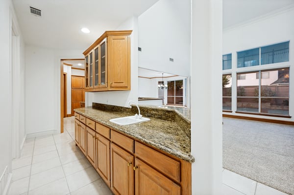 Spacious kitchen features ample storage and a bar area, seamlessly connecting to a bright living space.