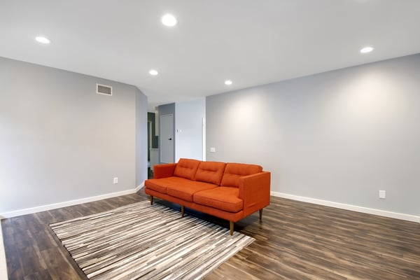 Spacious living area featuring modern décor, warm orange sofa, and inviting natural light throughout.