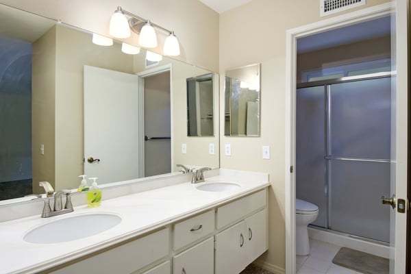 Spacious and modern bathroom featuring dual sinks, ample storage, and a separate shower area for convenience.