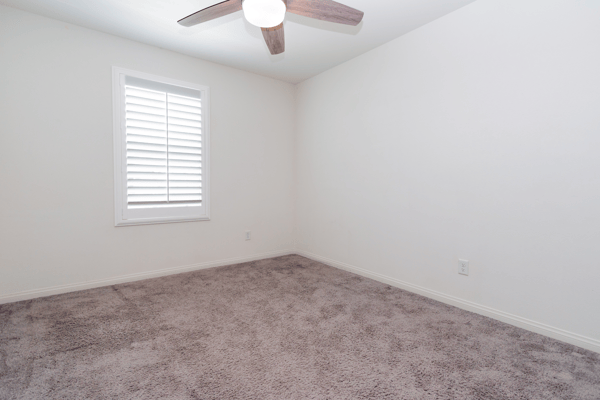Bright room featuring a ceiling fan and window shutters, perfect for personalizing your private space.