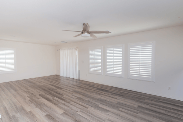 Spacious living area featuring ample natural light and sleek wood-style flooring, perfect for versatile layouts.