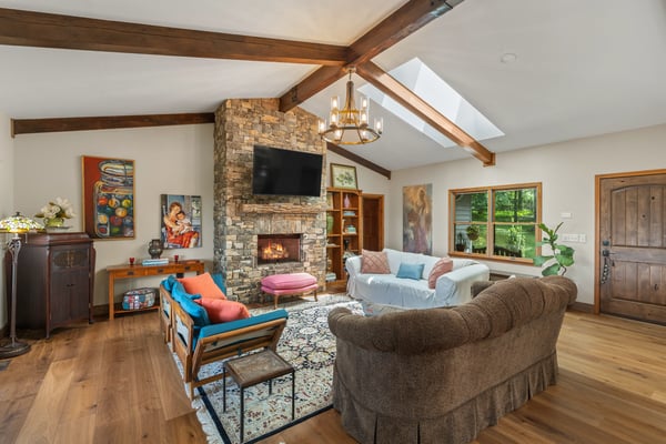 Bright and inviting living room with a stone fireplace, vaulted ceilings, and a cozy, open layout.
