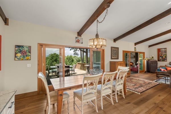 Bright and inviting dining area featuring exposed beams, large windows, and seamless indoor-outdoor access.