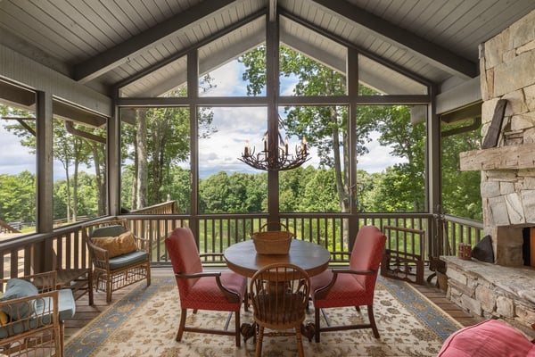 Bright, airy sunroom with panoramic views, featuring high ceilings, inviting seating, and a cozy fireplace.