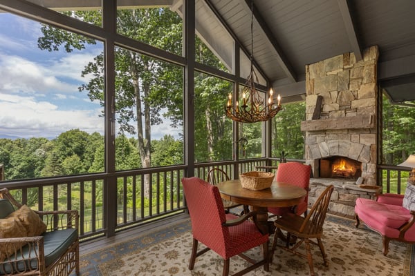 Bright and airy sunroom featuring a stone fireplace, perfect for cozy gatherings amidst nature views.