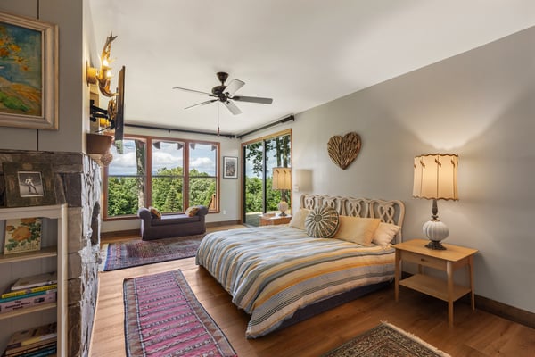 Spacious bedroom with large windows offering stunning views, cozy seating area, and tasteful decor throughout.