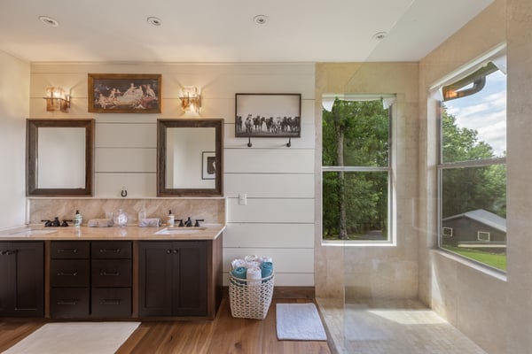Bright and spacious bathroom featuring dual sinks, large windows, and modern fixtures for a refreshing experience.
