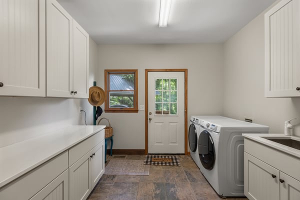 Bright and functional laundry room featuring ample cabinetry and convenient outdoor access. Ideal for everyday tasks.