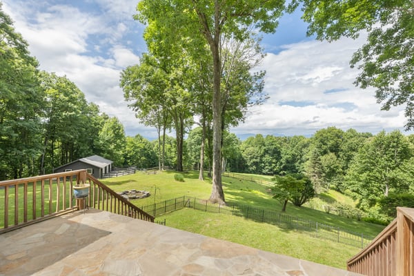 Spacious outdoor retreat featuring lush greenery, scenic views, and convenient access to a rustic outbuilding.