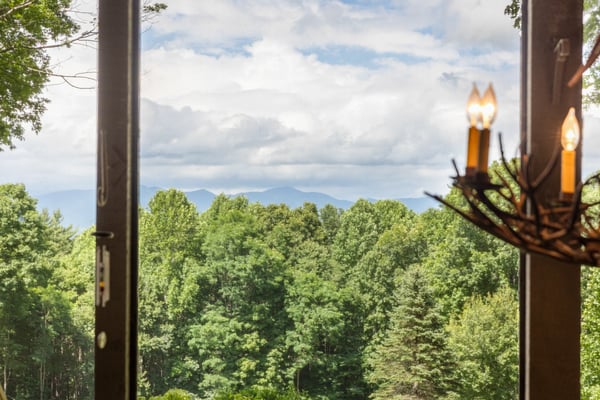 Breathtaking mountain views framed by expansive windows, surrounded by lush greenery for a peaceful retreat.