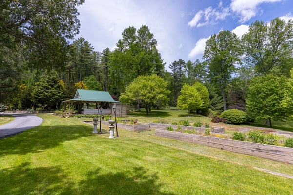 Spacious outdoor area featuring a lush garden, shaded gazebo, and scenic views of surrounding nature.