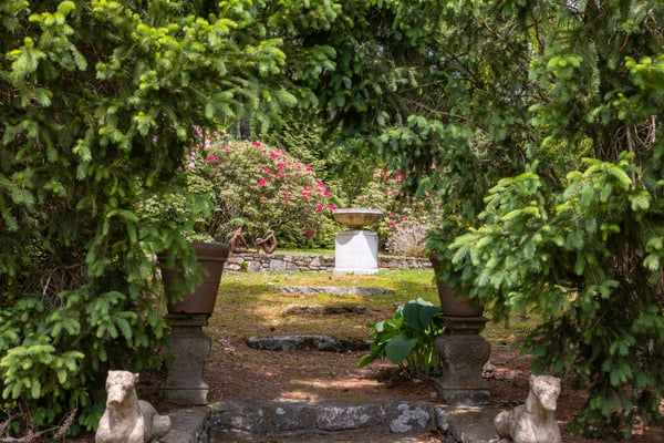 Discover a tranquil garden oasis, featuring lush greenery and a picturesque stone pathway leading to a fountain.