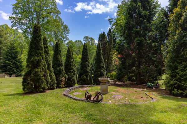 This expansive outdoor space features lush greenery and a unique stone birdbath, perfect for relaxation.