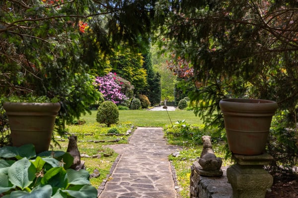 Discover a picturesque garden pathway leading to vibrant blooms and inviting greenery in this tranquil outdoor space.
