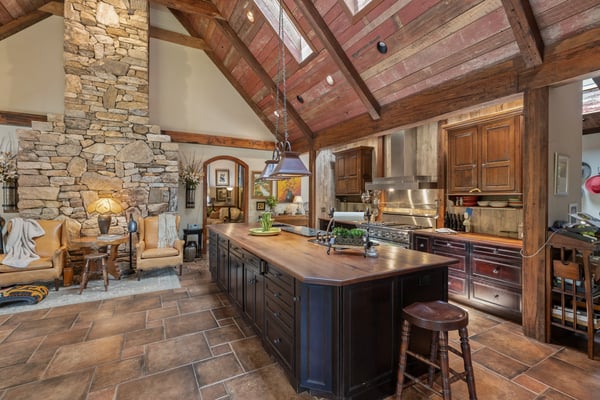 This spacious kitchen features a striking stone fireplace, high ceilings, and a large island for gatherings.