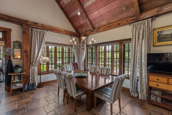 Inviting dining area featuring large windows, rustic beams, and ample space for gatherings or entertaining.