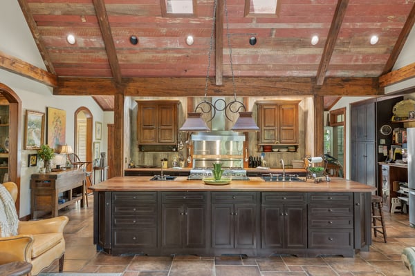 Discover this spacious kitchen featuring a large island, exposed beams, and rich wooden cabinetry, ideal for gatherings.