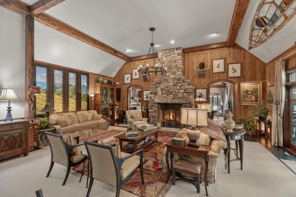 Spacious living area featuring a stunning stone fireplace and large windows with picturesque mountain views.