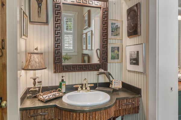 Unique bathroom featuring custom decor, artistic sink design, and a mix of vintage artwork for a personalized touch.
