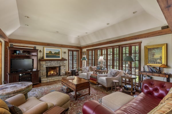 Spacious living room features abundant natural light, a cozy fireplace, and picturesque views through large windows.