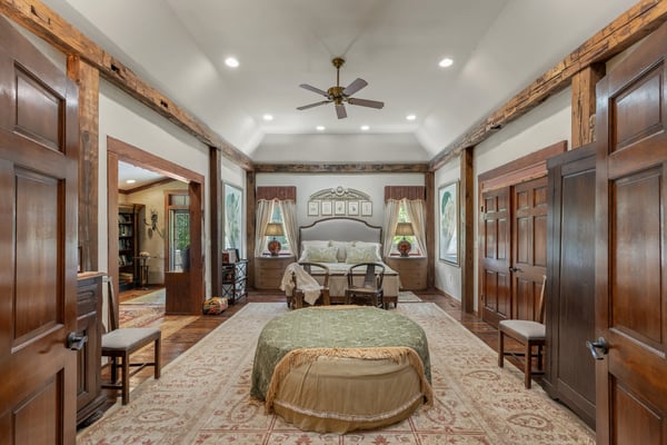 Spacious bedroom featuring rustic beams, large windows, and inviting seating, perfect for relaxation and comfort.