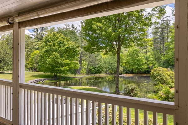 Beautiful views of a tranquil pond and vibrant greenery from the inviting covered porch.