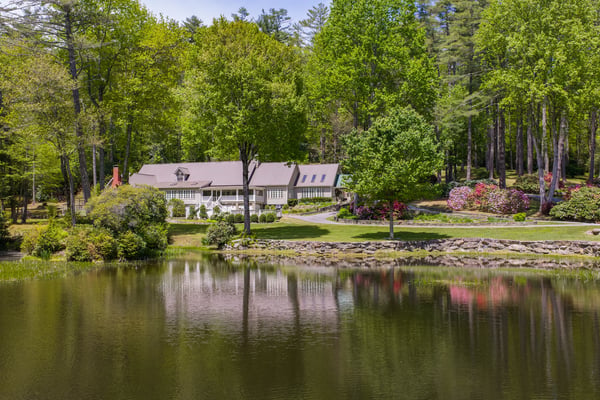 Idyllic waterfront property surrounded by lush greenery, featuring spacious interiors and picturesque landscaping throughout.
