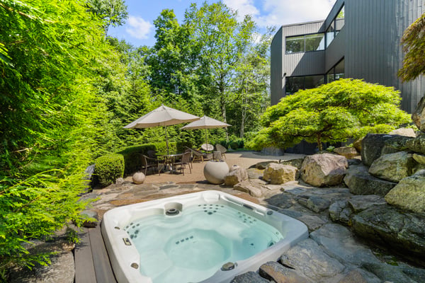 Private outdoor oasis featuring a hot tub and lush landscaping, perfect for relaxation and entertaining.