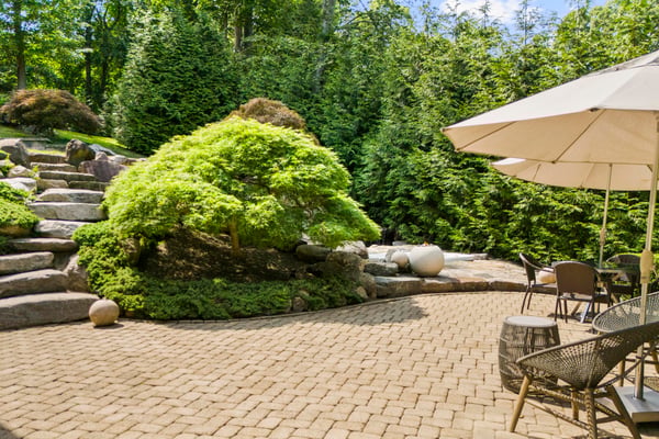 Discover a tranquil garden retreat featuring a stone pathway, lush greenery, and inviting seating areas.