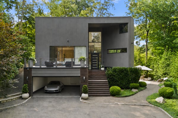 Contemporary home set among lush greenery, featuring a spacious garage and inviting outdoor living area.