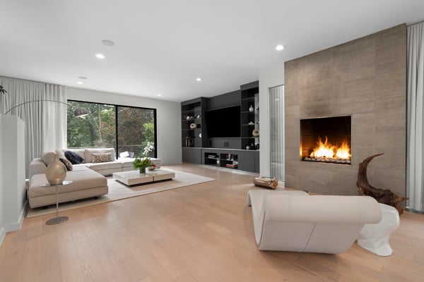 Bright and spacious living area featuring a sleek fireplace and large windows that invite nature indoors.