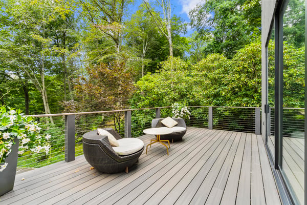 Spacious outdoor deck surrounded by lush greenery, perfect for relaxation and entertaining in nature.