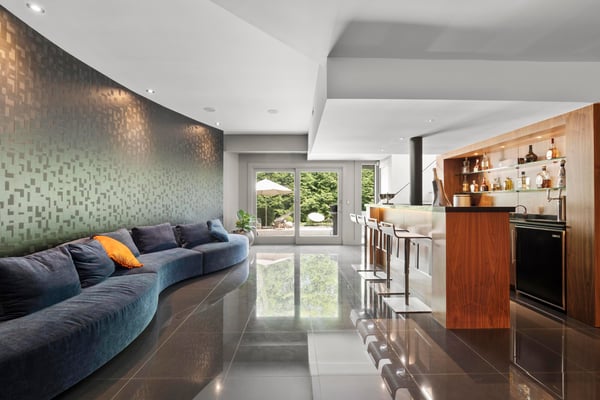 Contemporary open-concept living space with curved seating, sleek bar area, and seamless outdoor access.