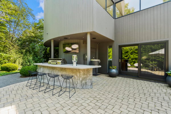 This outdoor space features a sleek kitchen island perfect for entertaining in a lush, private setting.