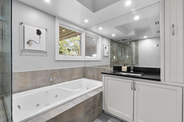 Bright and spacious bathroom featuring a large soaking tub, dual sinks, and modern fixtures.