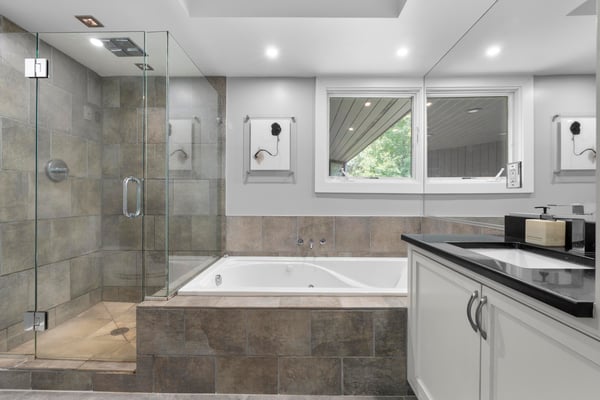 This modern bathroom features a glass-enclosed shower, soaking tub, and abundant natural light.