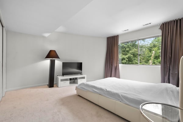 Bright and spacious bedroom featuring large windows, modern TV setup, and ample natural light.