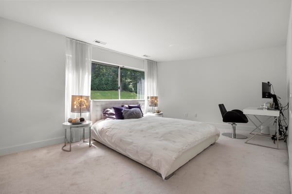 Bright and spacious bedroom featuring large windows, a cozy bed, and dedicated workspace for productivity.