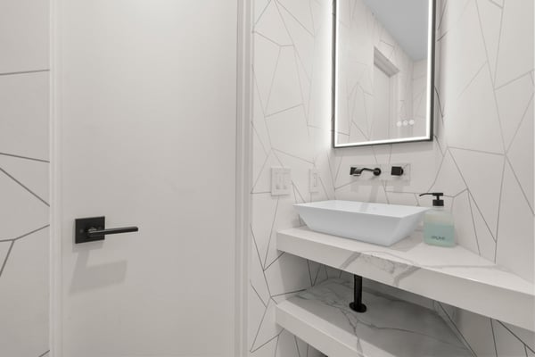 Modern bathroom featuring geometric tile accents, minimalist fixtures, and a sleek, illuminated mirror.