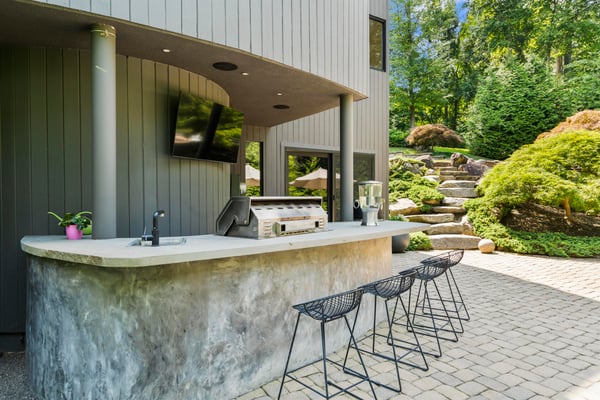 Modern outdoor bar area with a sleek countertop, perfect for entertaining amid lush landscaping.