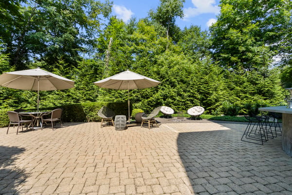 Discover an inviting outdoor space featuring ample seating, shade umbrellas, and a lush green backdrop.
