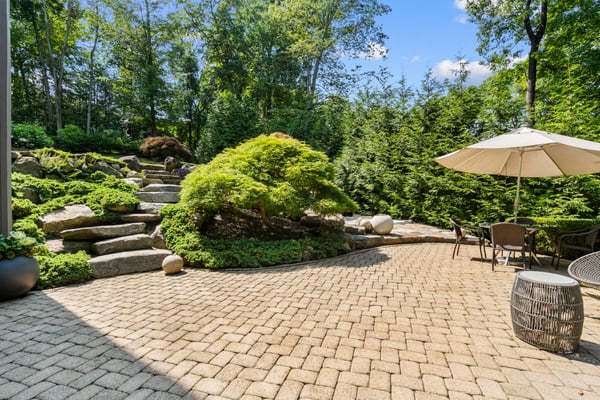 Discover a tranquil garden oasis featuring stone pathways, lush greenery, and an inviting outdoor seating area.