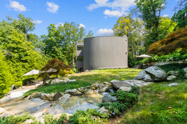 Nestled in nature, this unique home features a landscaped yard and striking architecture surrounded by lush greenery.