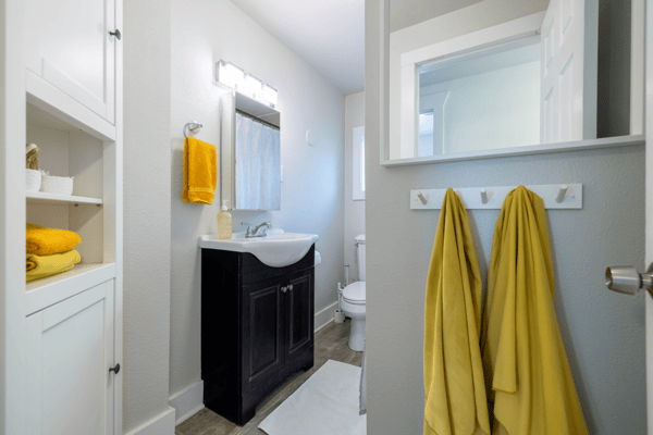 Bright and clean bathroom featuring modern fixtures, ample storage, and vibrant yellow accents for a fresh look.