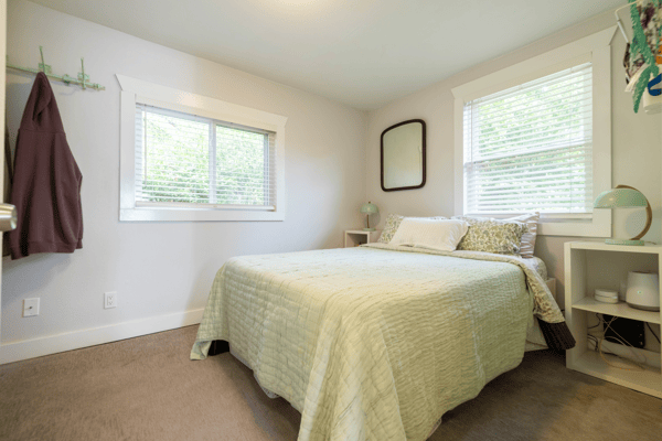 Cozy bedroom featuring natural light, comfortable bedding, and functional storage, perfect for relaxation and rest.